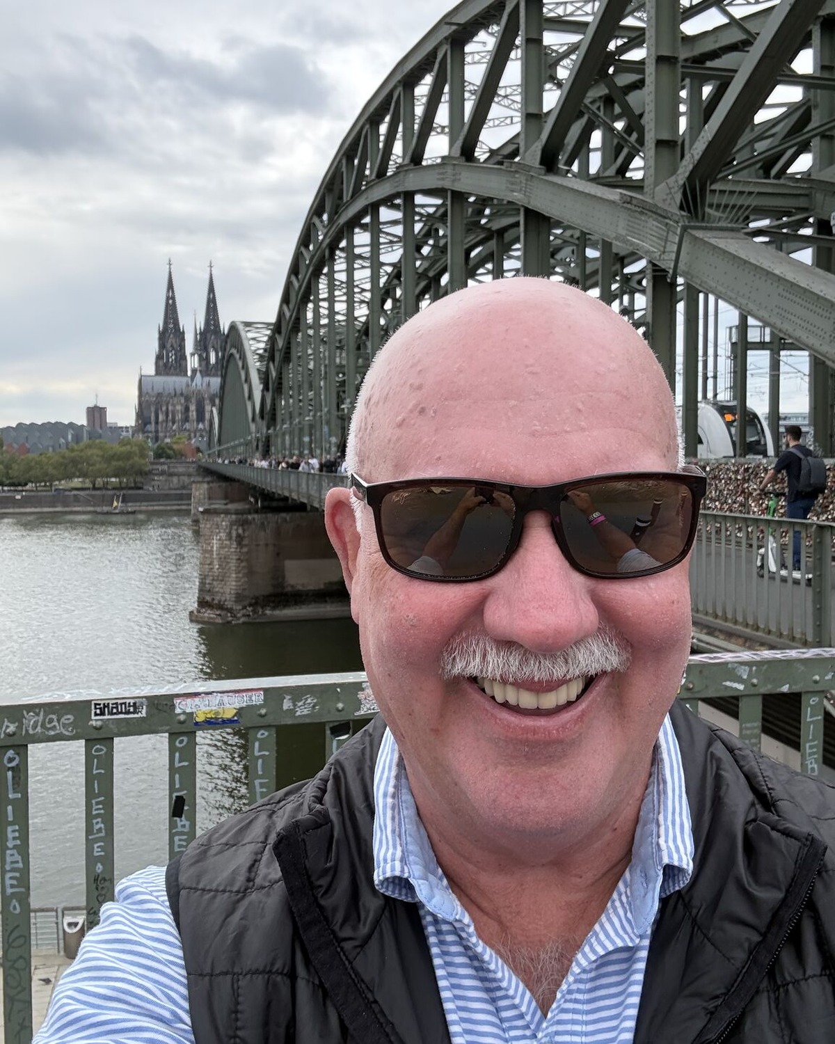 Hank Howie smiling on Cologne’s Hohenzollern Bridge with Cologne Cathedral behind him during Gamescom 2026