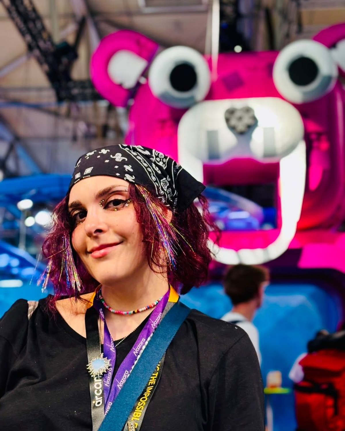 Ruslana Kruchek at Gamescom 2026, wearing a black bandana with a bright pink creature display behind her