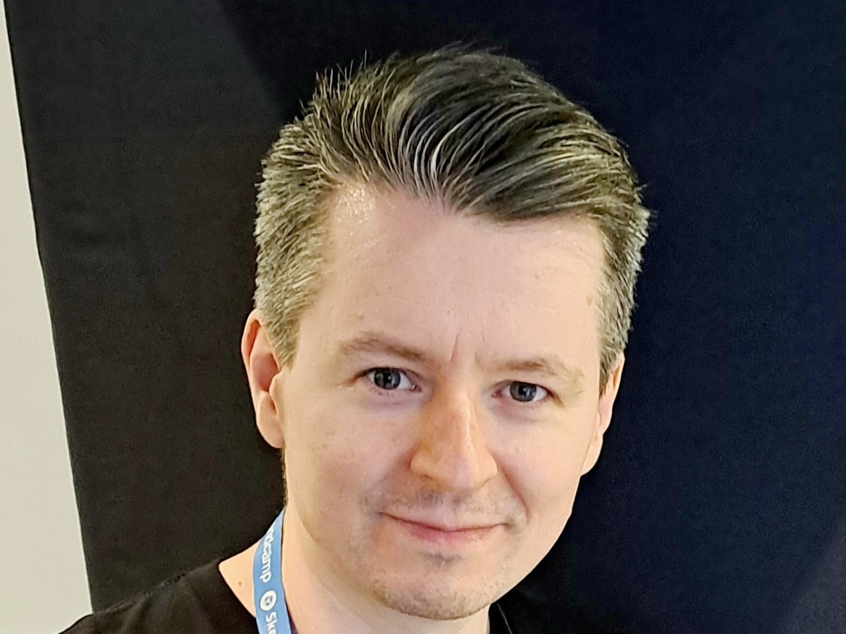 Tommy Thompson at Gamescom 2026, wearing an AI and Games shirt and event lanyard
