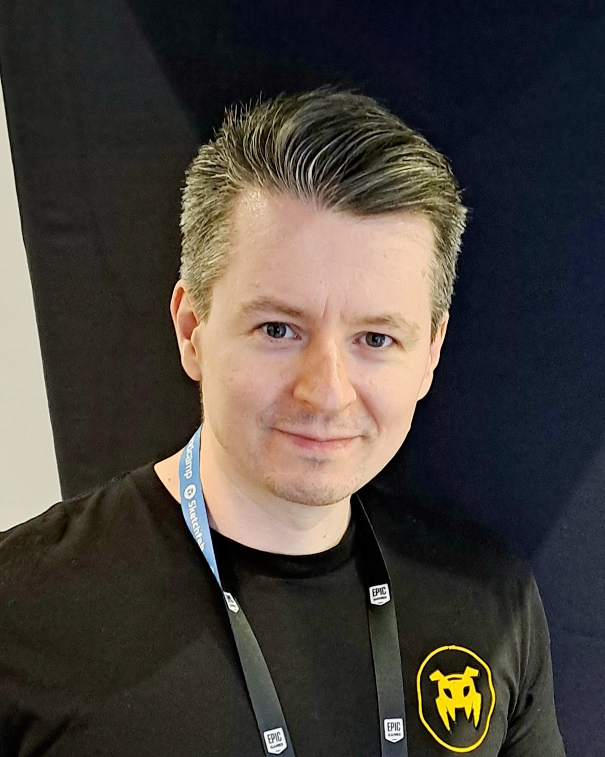 Tommy Thompson at Gamescom 2026, wearing an AI and Games shirt and event lanyard